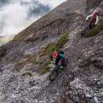 Två mountainbikecyklister bromsar i en brant, stenig utförslöpa
