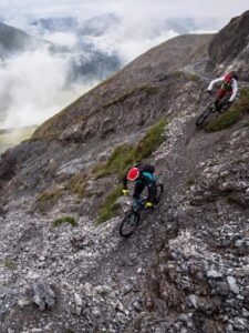 Två mountainbikecyklister bromsar i en brant, stenig utförslöpa