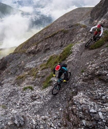 Två mountainbikecyklister bromsar i en brant, stenig utförslöpa