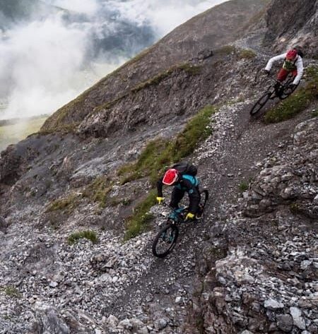 Två mountainbikecyklister bromsar i en brant, stenig utförslöpa