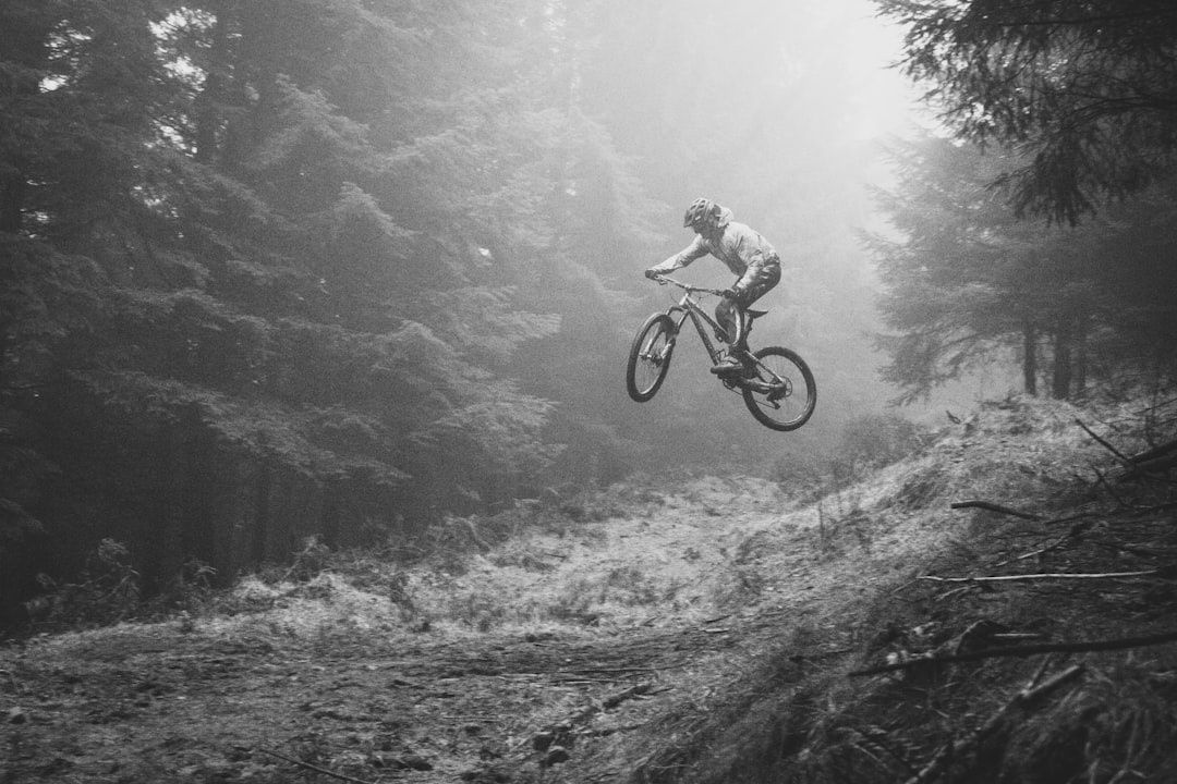 Mountainbikecyklist hoppar över en brant skogsstig i dimma