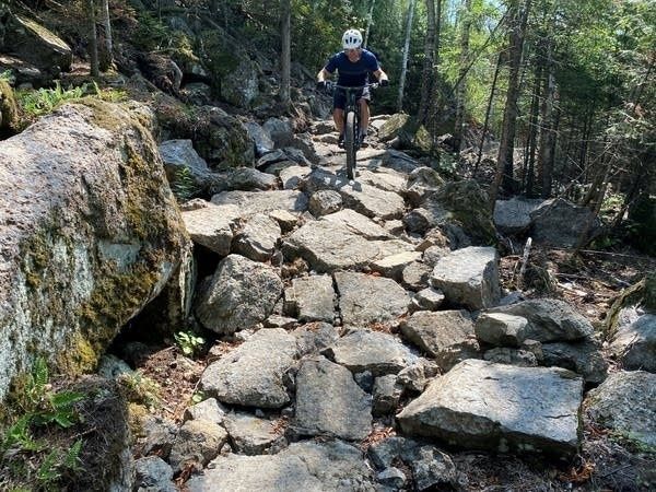 Cyklist kör mountainbike över en stenig skogsstig
