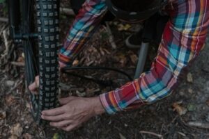 Cyklist monterar ett grovt mountainbikedäck med händerna